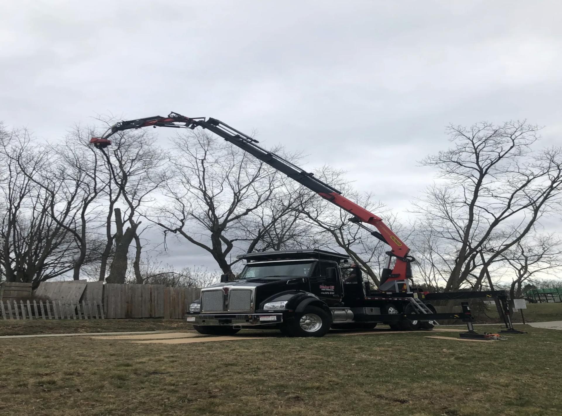 A red machine is trimming the trees.